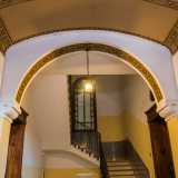 Gli stessi elementi decorativi tornano ad abbellire la parte interna di un arco che precede le scale e poggia su dei capitelli a volute